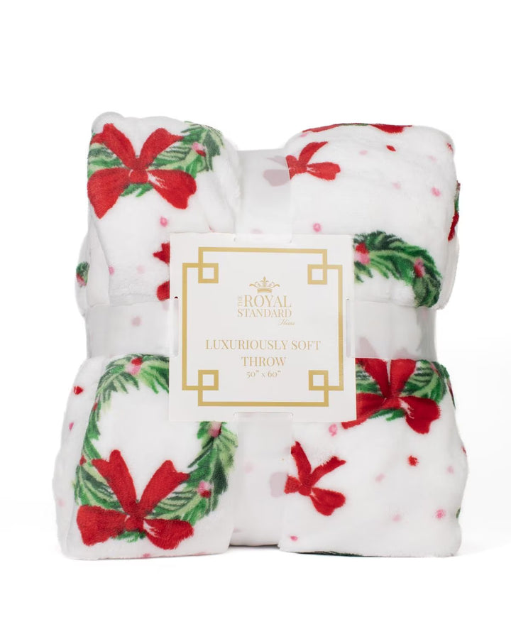Christmas-themed throw blanket with red bows and green wreaths on a white background