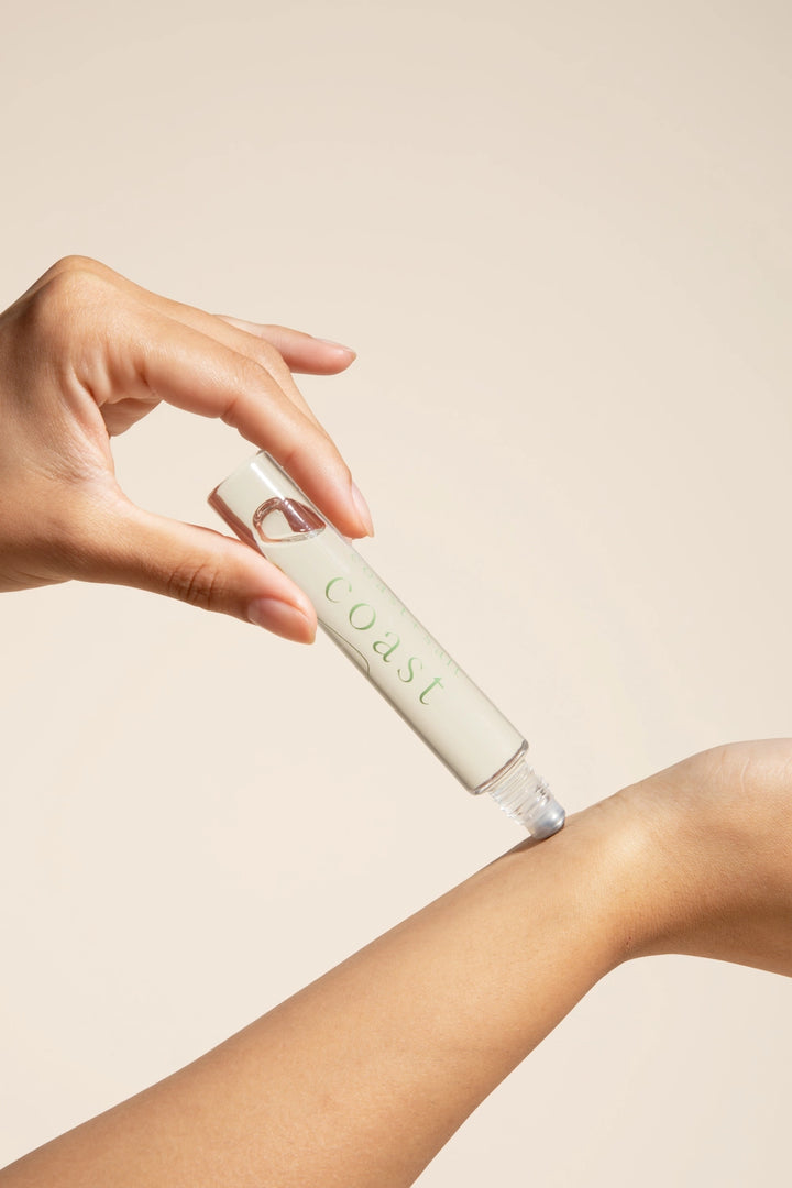 Someone showing application of Coast + Salt  Coast Roll-on perfume bottle 