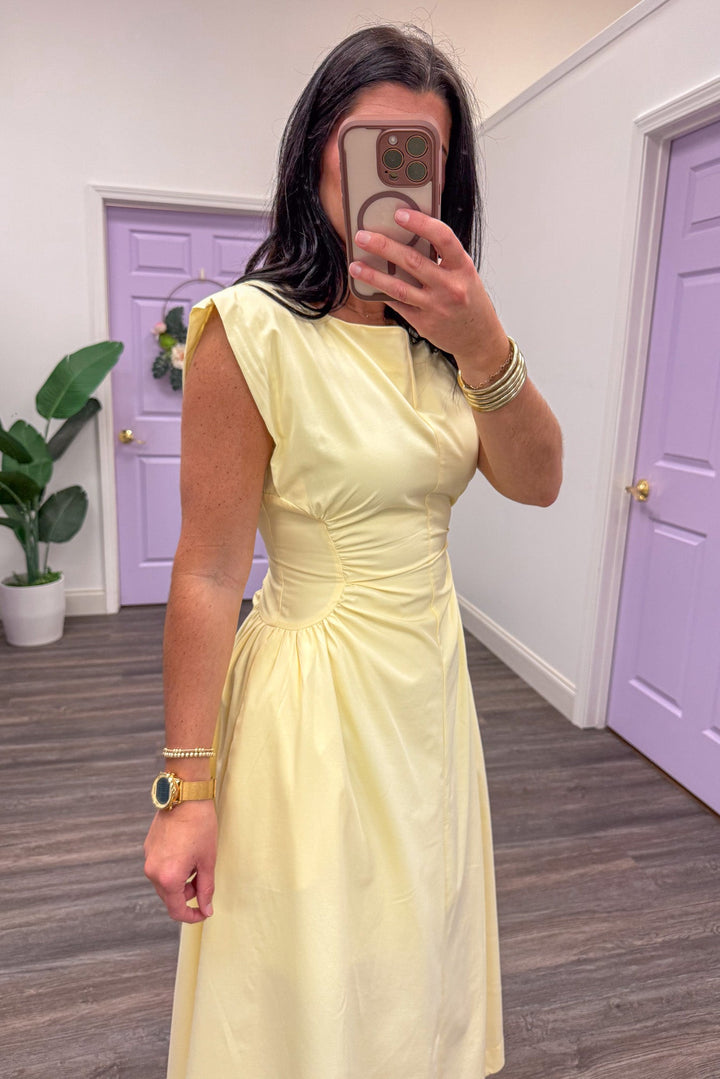 Side view of yellow sleeveless midi dress with cinched waist
