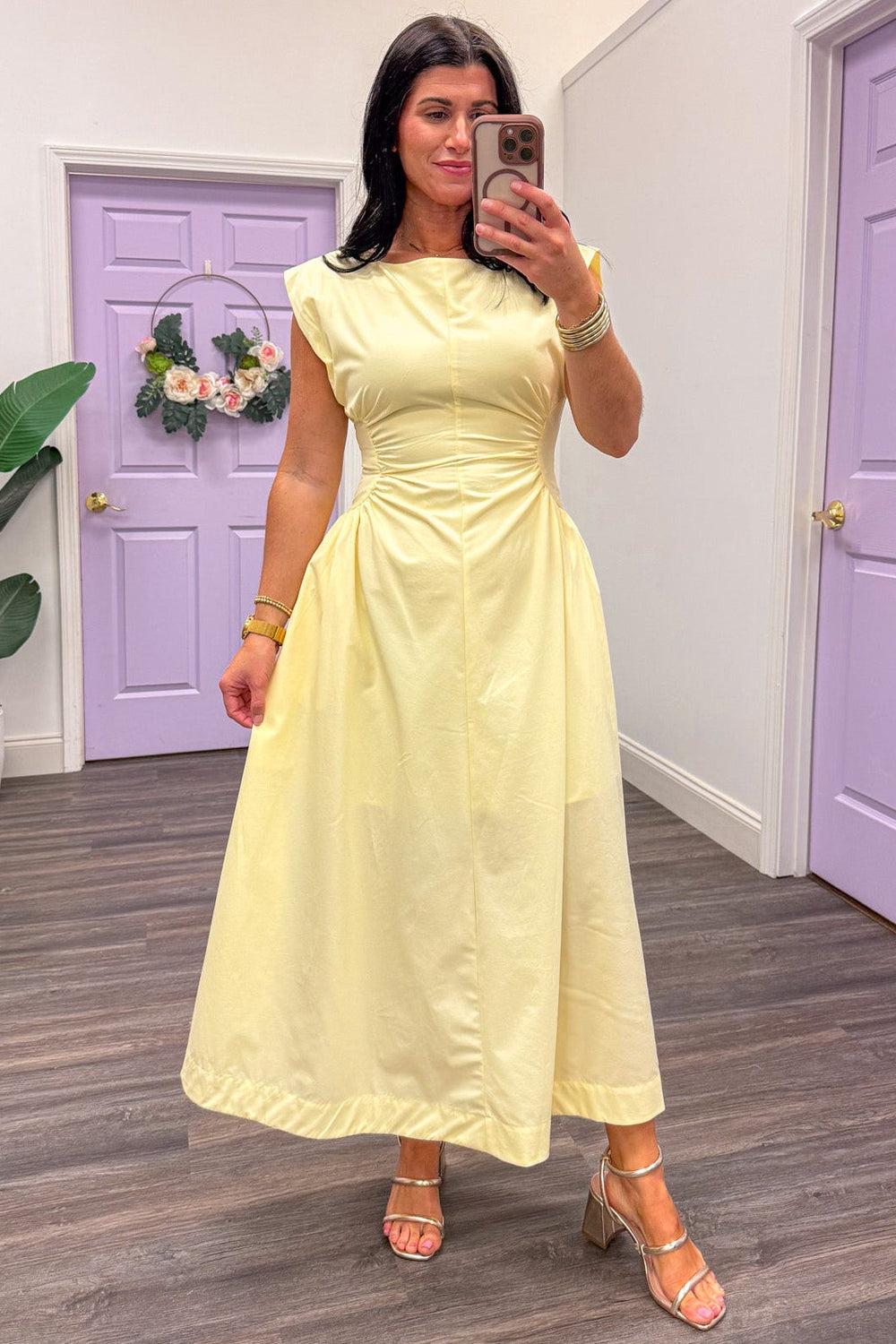 Women's cinched panel yellow midi dress paired with gold bangles and sandals 