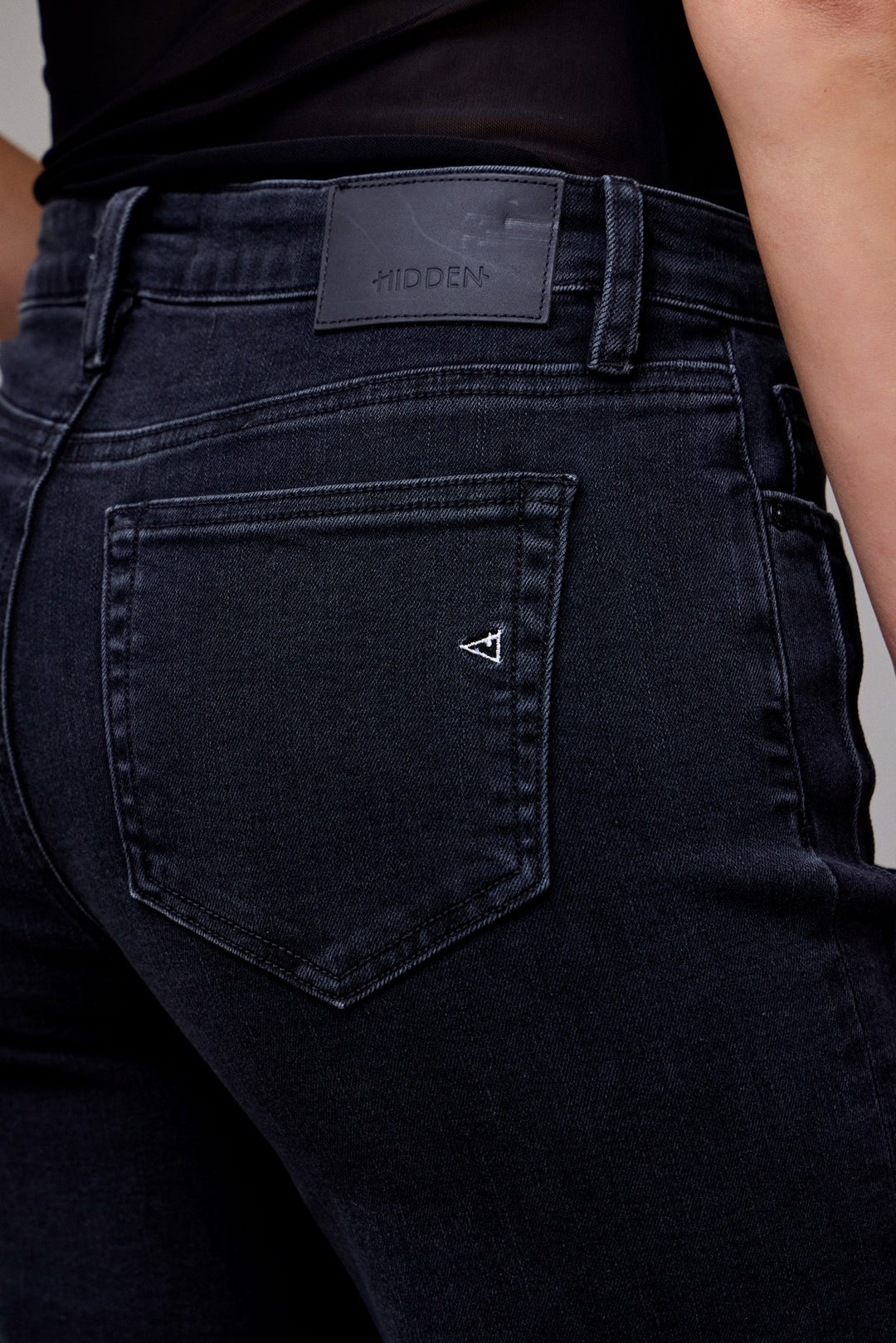 Close-up of mid-rise waist and back pockets on black flare jeans by Hidden Jeans