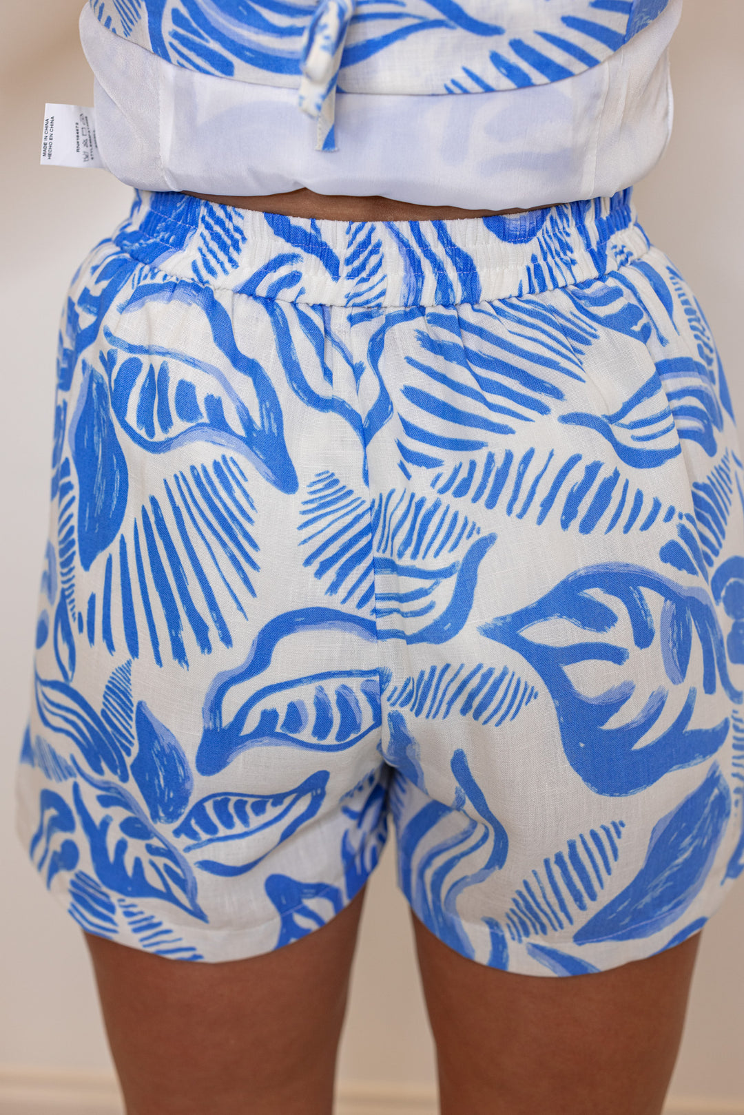 Women's off white sleeveless top and shorts set in blue palm leaf print by &merci showing up close back view of bottoms