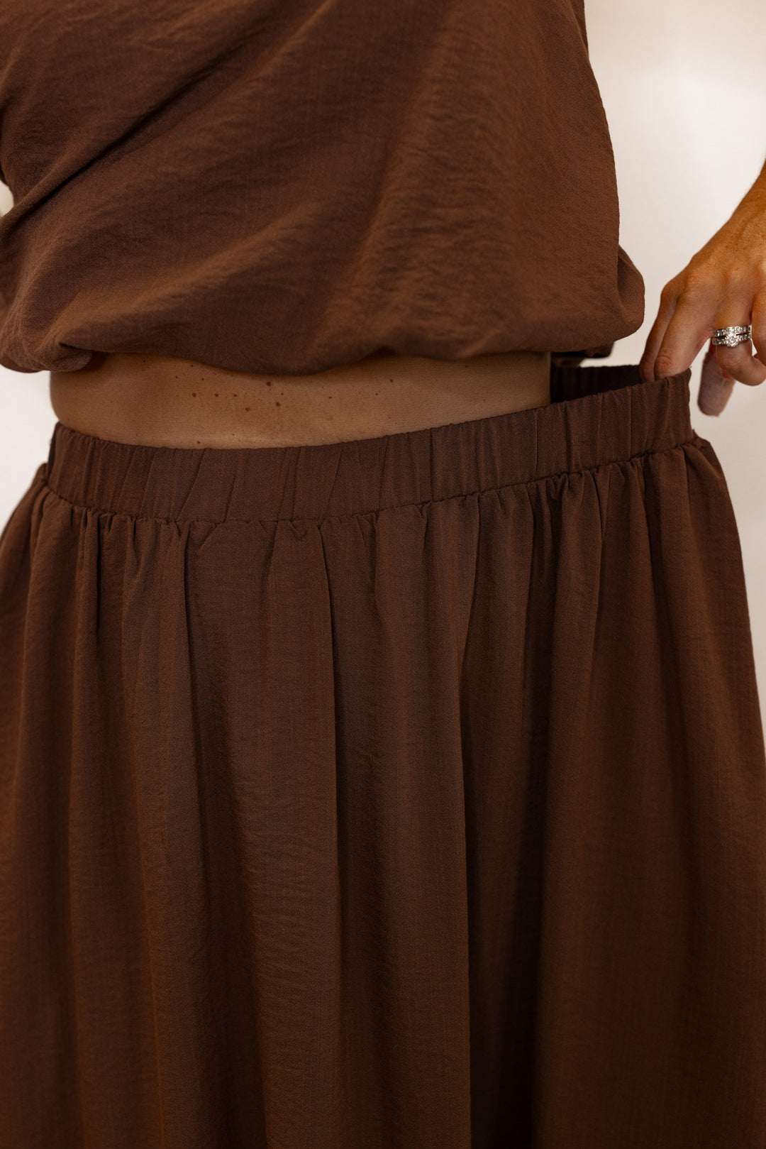 Women's espresso brown textured midi skirt with pleats by Entro showing elastic waistband