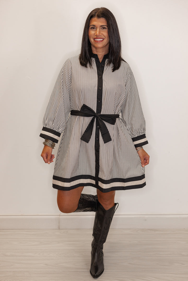 Women's striped white and black belted dress paired with black western boots