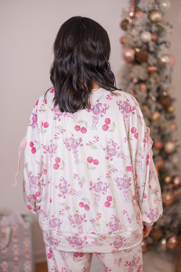 Women's white pajama lounge top with pink cherry santa print and bow tie details by Peach Love California showing up close back view