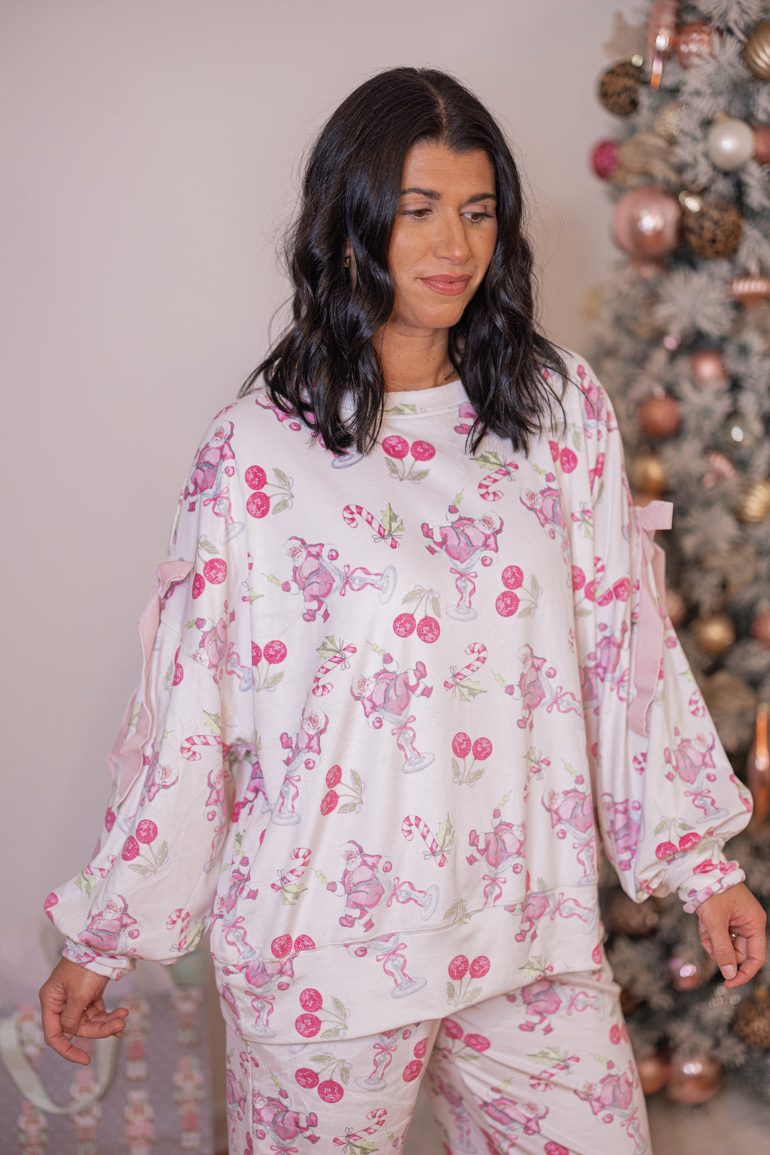 Women's white pajama lounge top with pink cherry santa print and bow tie details by Peach Love California showing slight side view