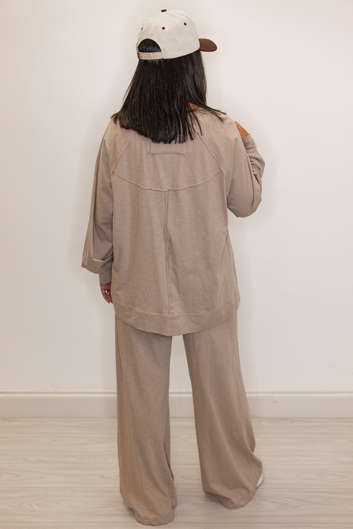 Back view beige athleisure pants and long sleeve top set with a cap