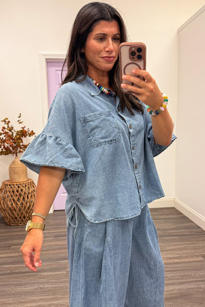 washed blue denim button front short sleeve top with cinch drawstring sides and one chest pocket