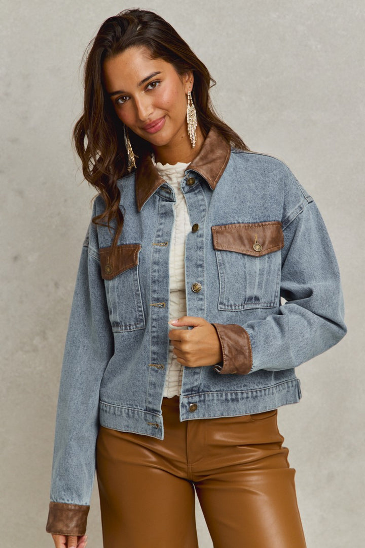 denim jacket with brown leather trim holding
