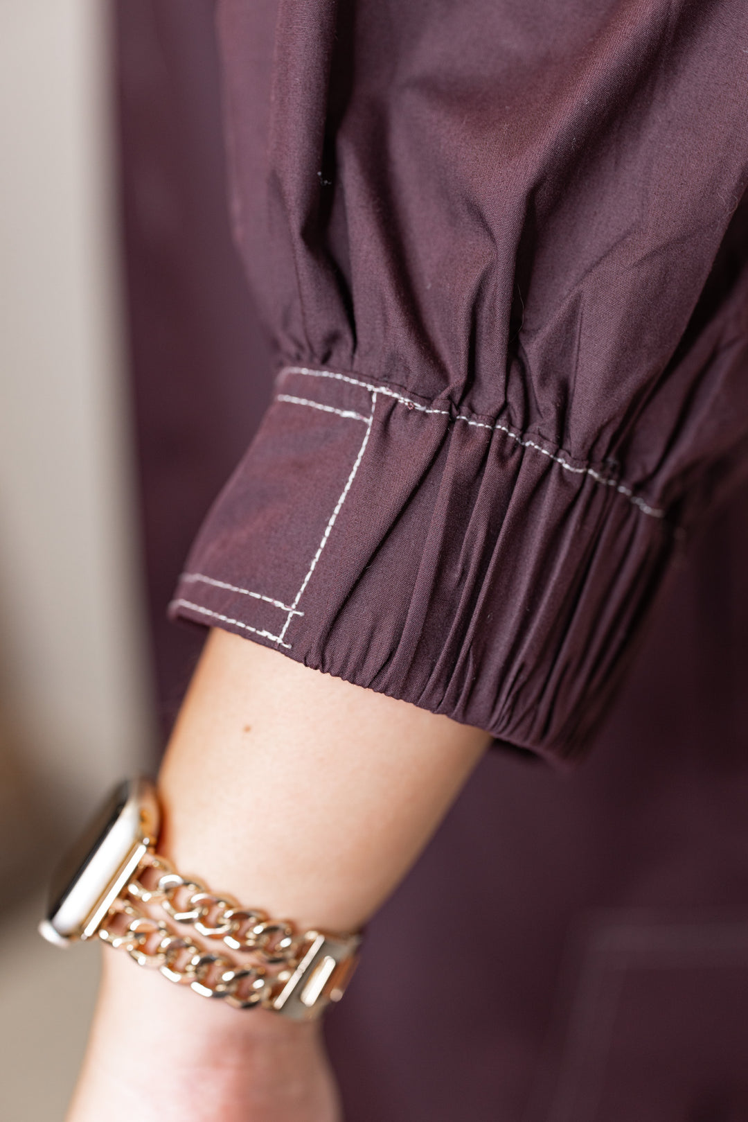 Women's chocolate brown mini dress with cream contrasting stitching throughout by Entro showing up close view of lantern sleeve detail