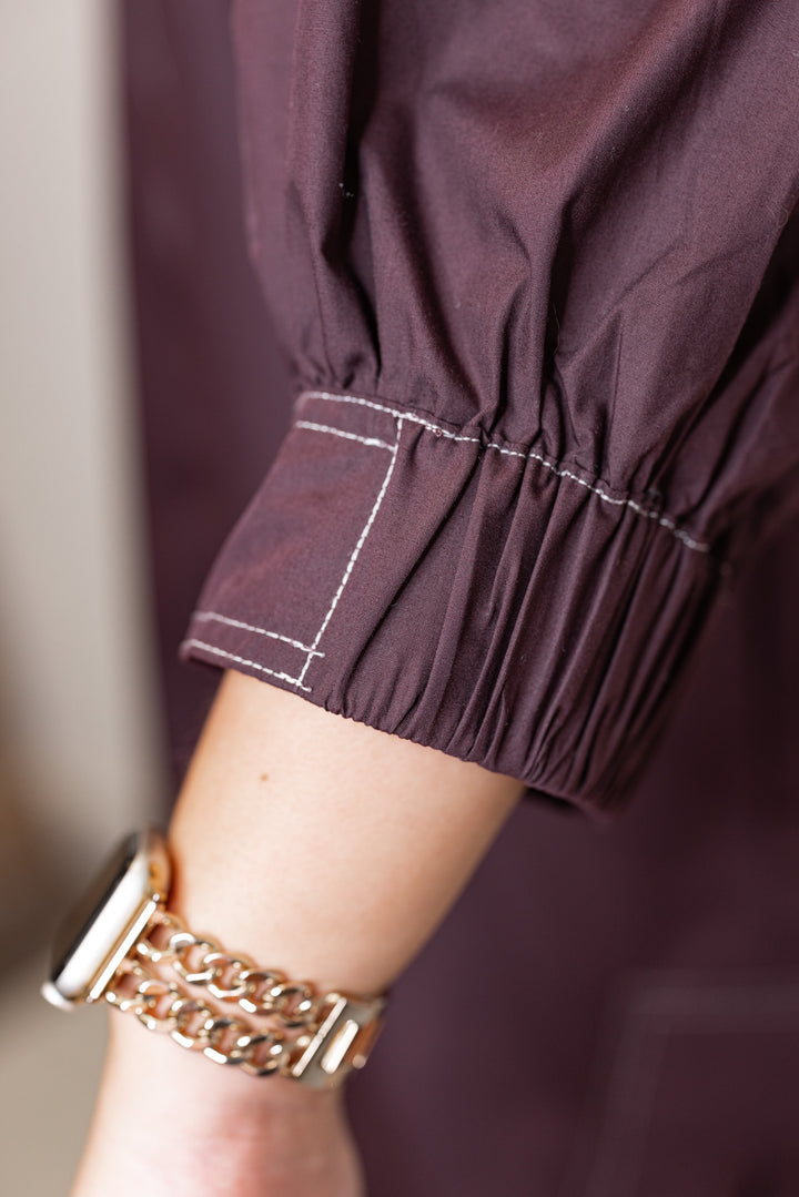 Women's chocolate brown mini dress with cream contrasting stitching throughout by Entro showing up close view of lantern sleeve detail