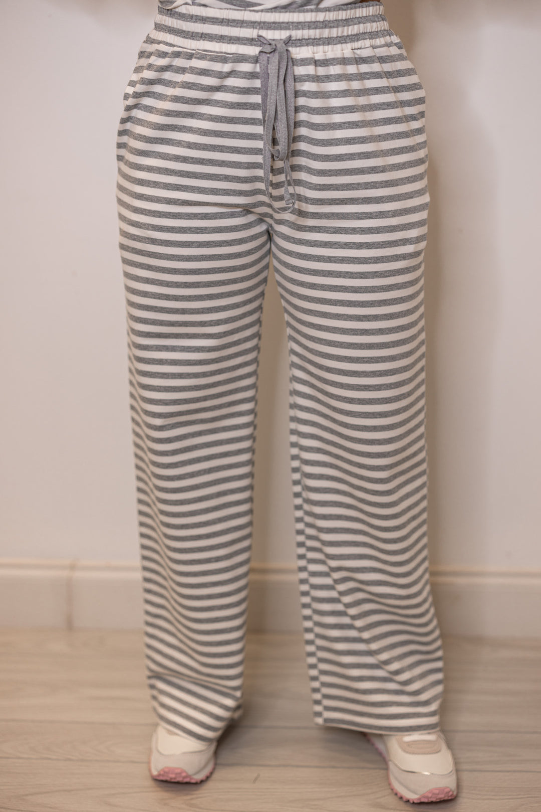 Women's grey striped lounge pants showing stretch drawstring waist