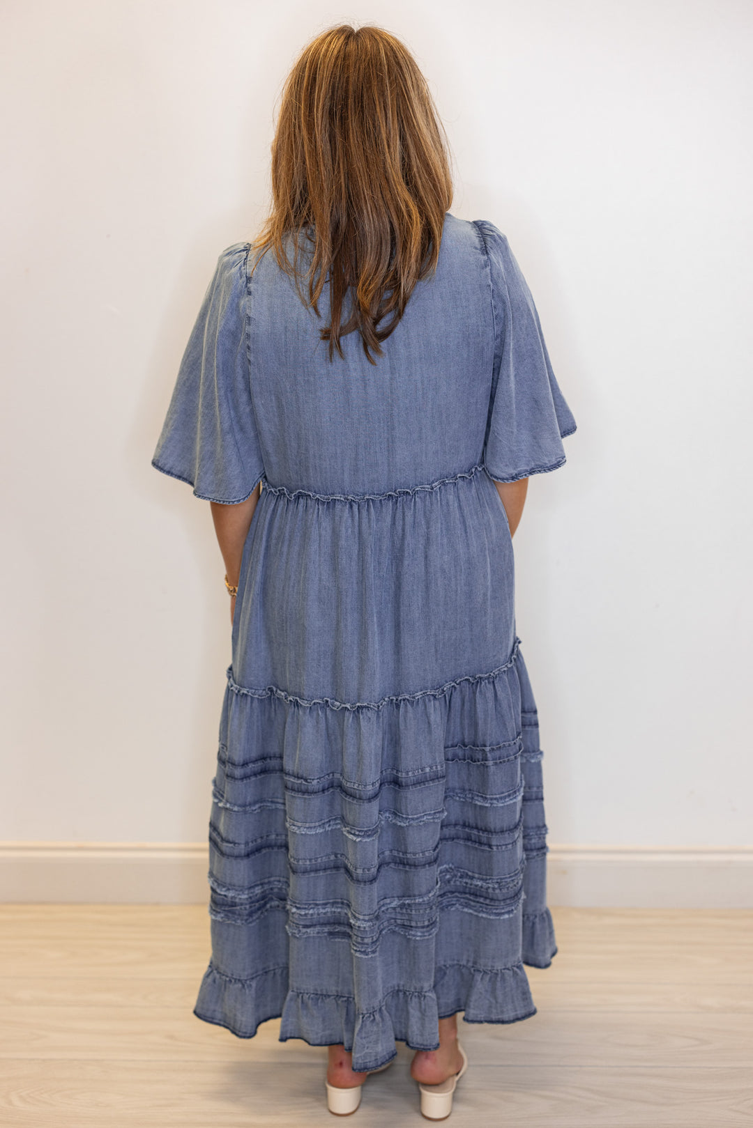 Women's washed blue chambray denim ruffle tiered midi dress with frayed details by Easel showing full back view