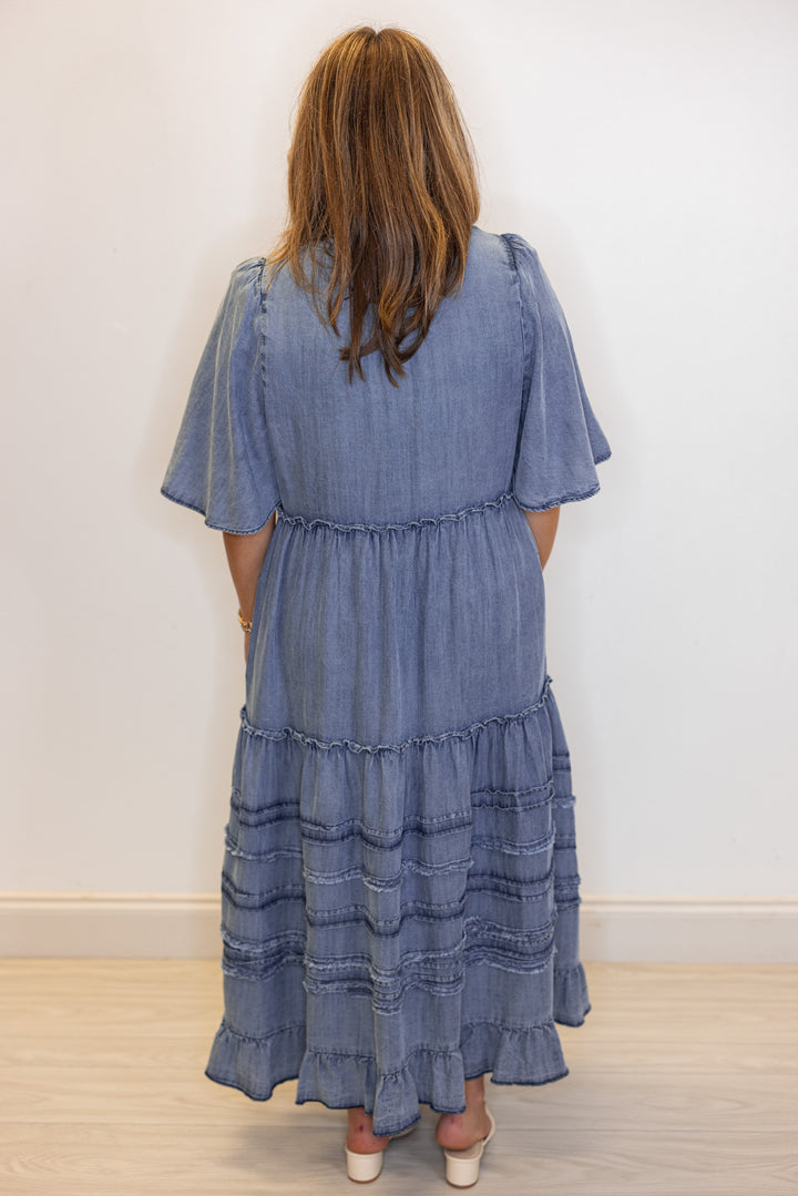 Women's washed blue chambray denim ruffle tiered midi dress with frayed details by Easel showing full back view