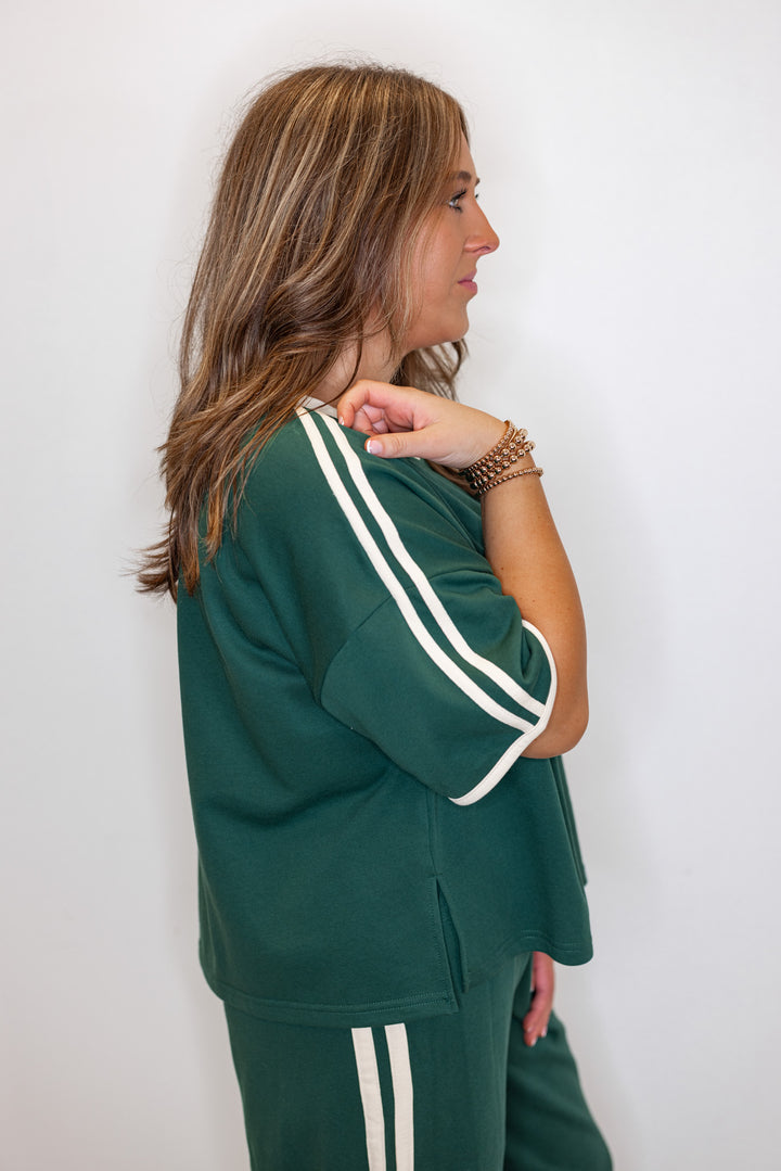 Women's hunter green french terry knit top with cream stripes on the sleeve by Entro showing up close, side view