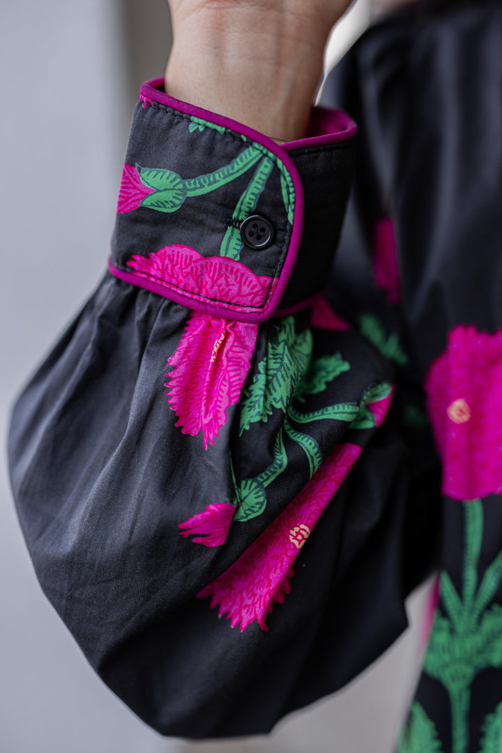 Women's black midi dress with hot pink floral print and hot pink piping trim by Jodifl showing up close of sleeve detail