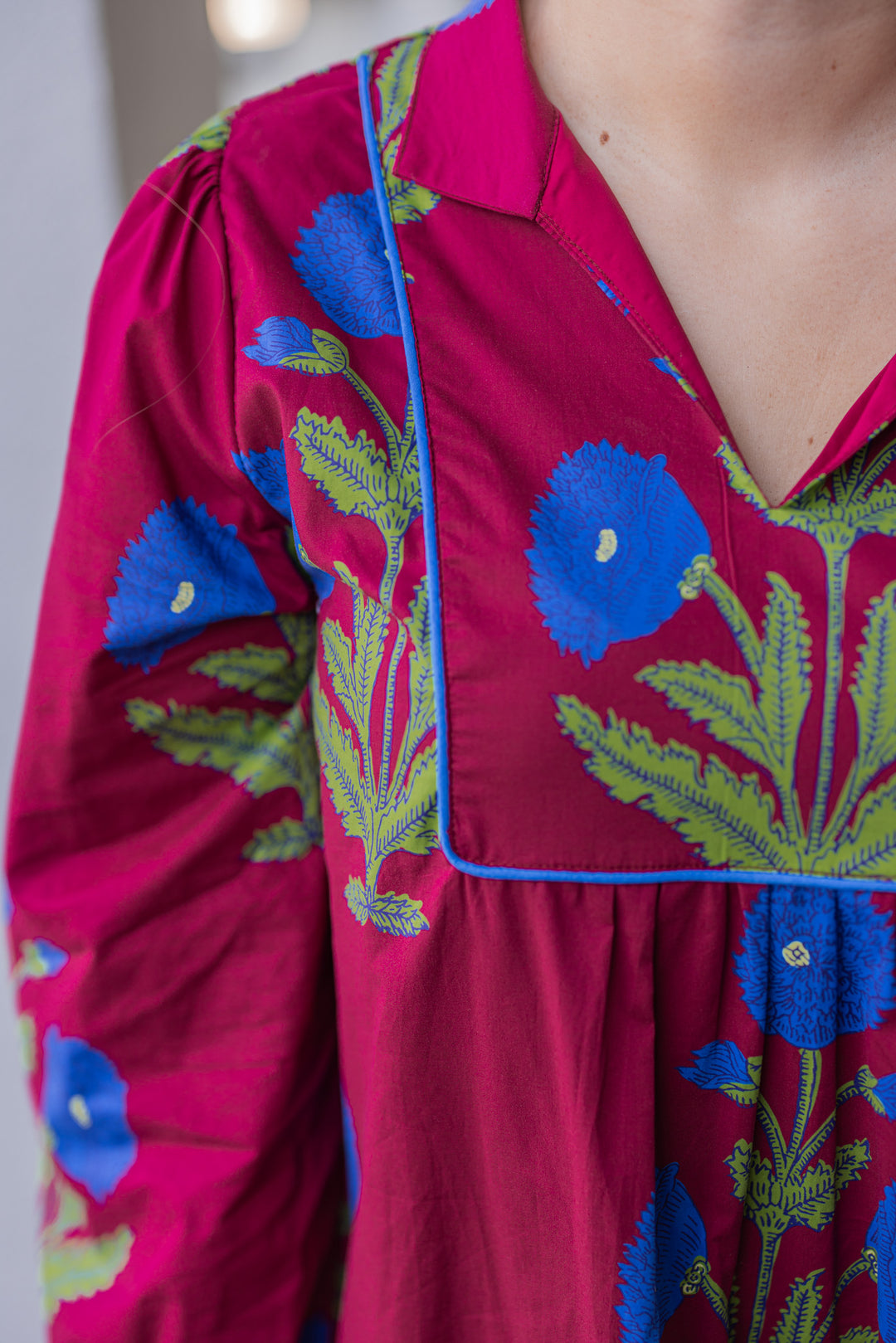 Women's burgundy midi dress by Jodifl showing up close view of dark blue floral print and dark blue piping trim