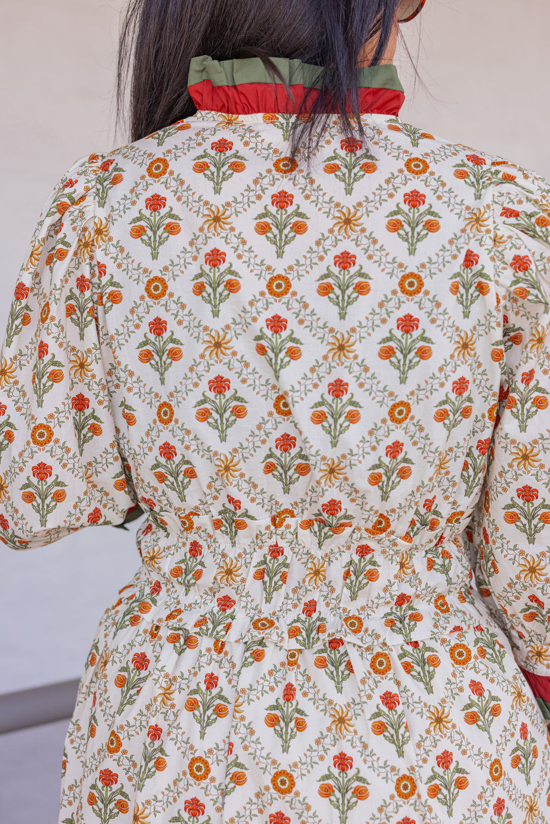 Women's ecru midi dress with orange and green floral print and ruffle trim by Entro showing up close back view