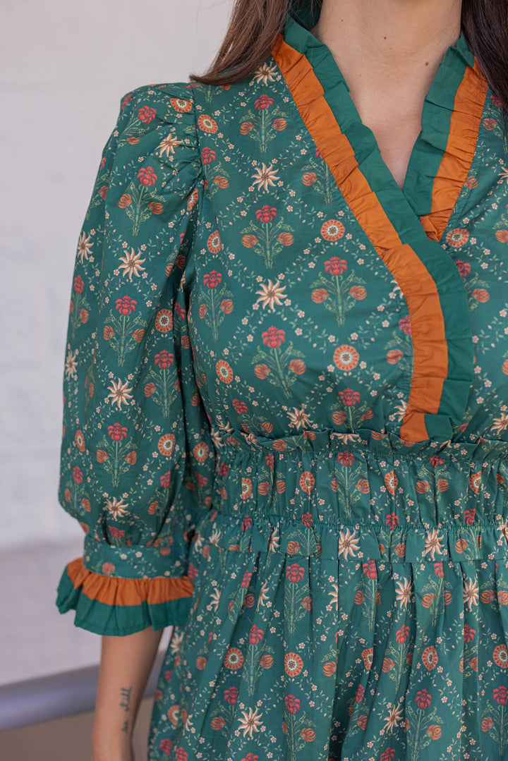 Women's hunter green midi dress with rust and taupe floral print and ruffle trim by Entro showing up close look at floral details