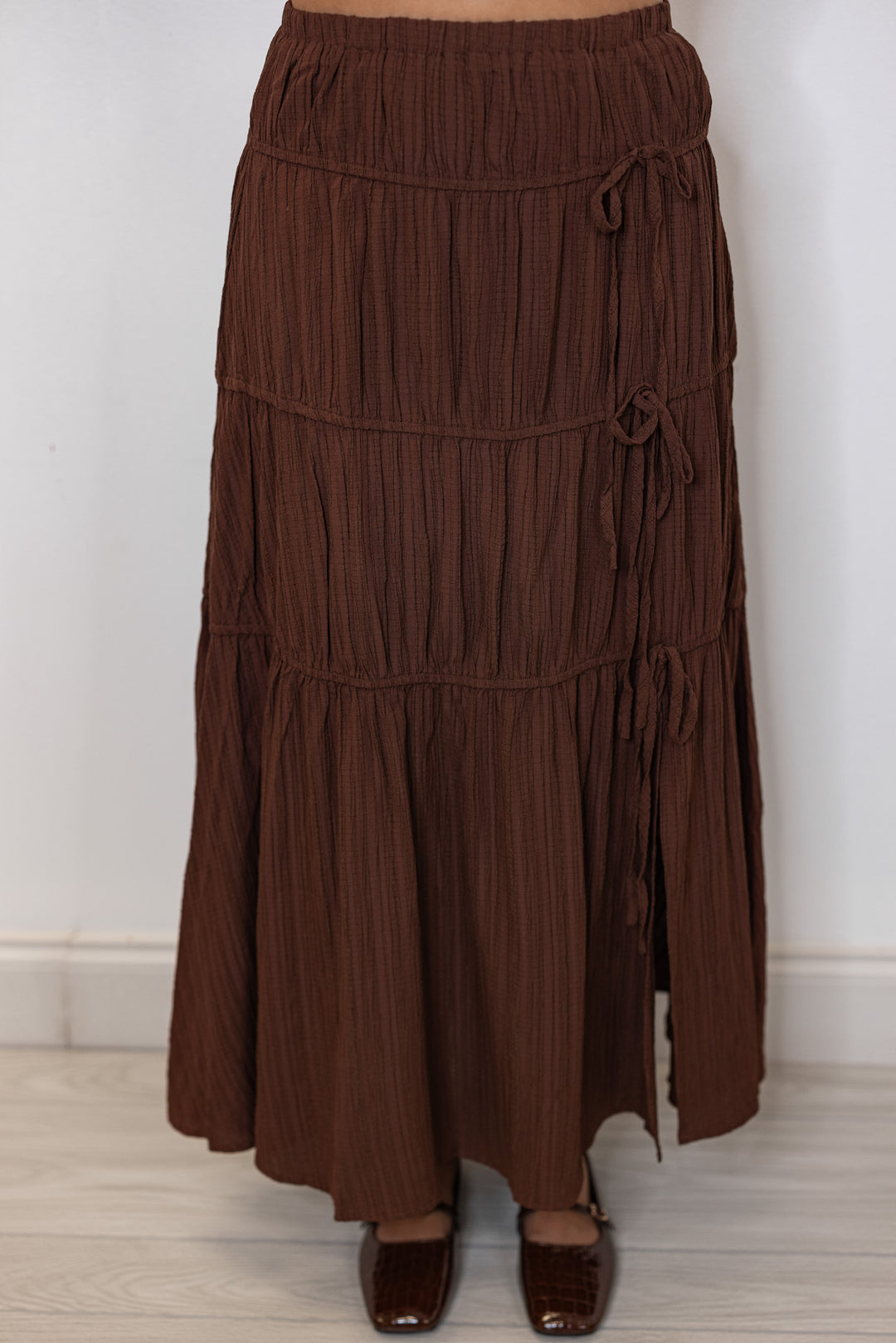 Women's pleated chocolate brown tiered midi skirt with bow ties down one side by In February showing up close front view