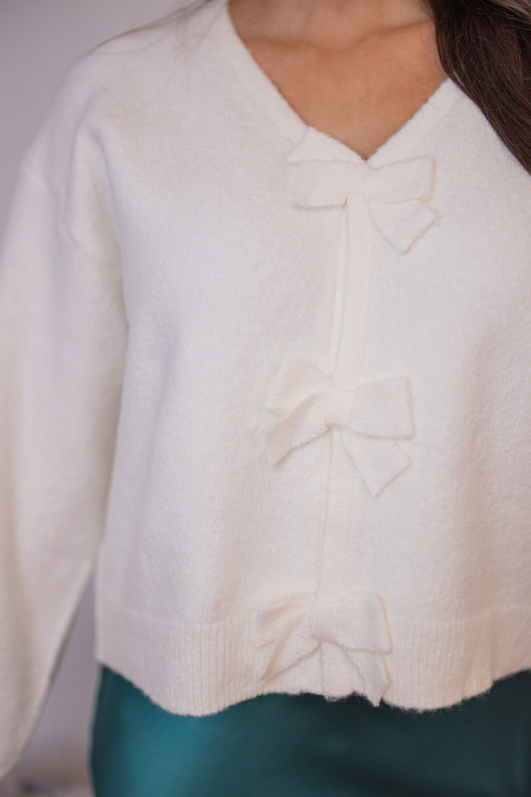 Women's cropped off white sweater with snap front bow tie closures by Wishlist showing up close bodice view