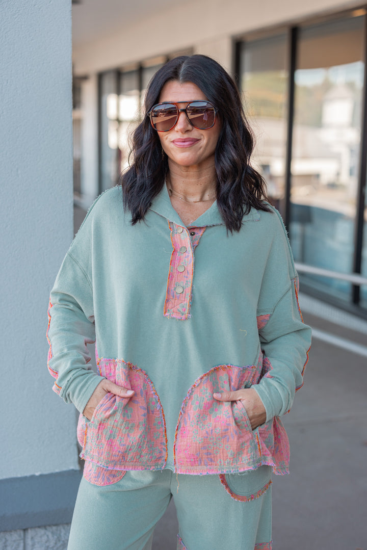 Women's french terry knit sage pullover top with frayed floral patch gauze details by Easel showing front pockets