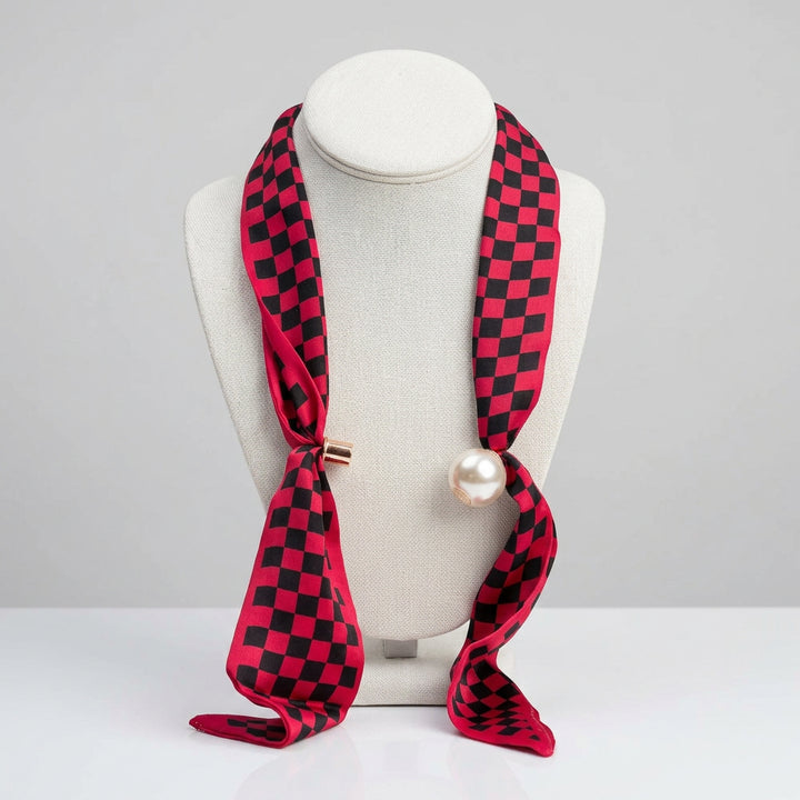 A pink and black checkered silk scarf with a single white pearl bead 
