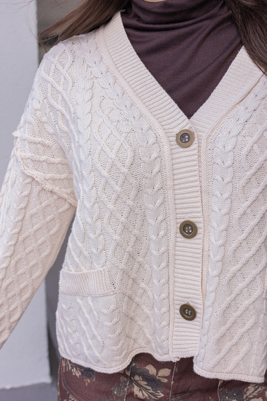 Women's cable knit button front sweater cardigan in ecru with ribbed trim by Entro showing up close front view