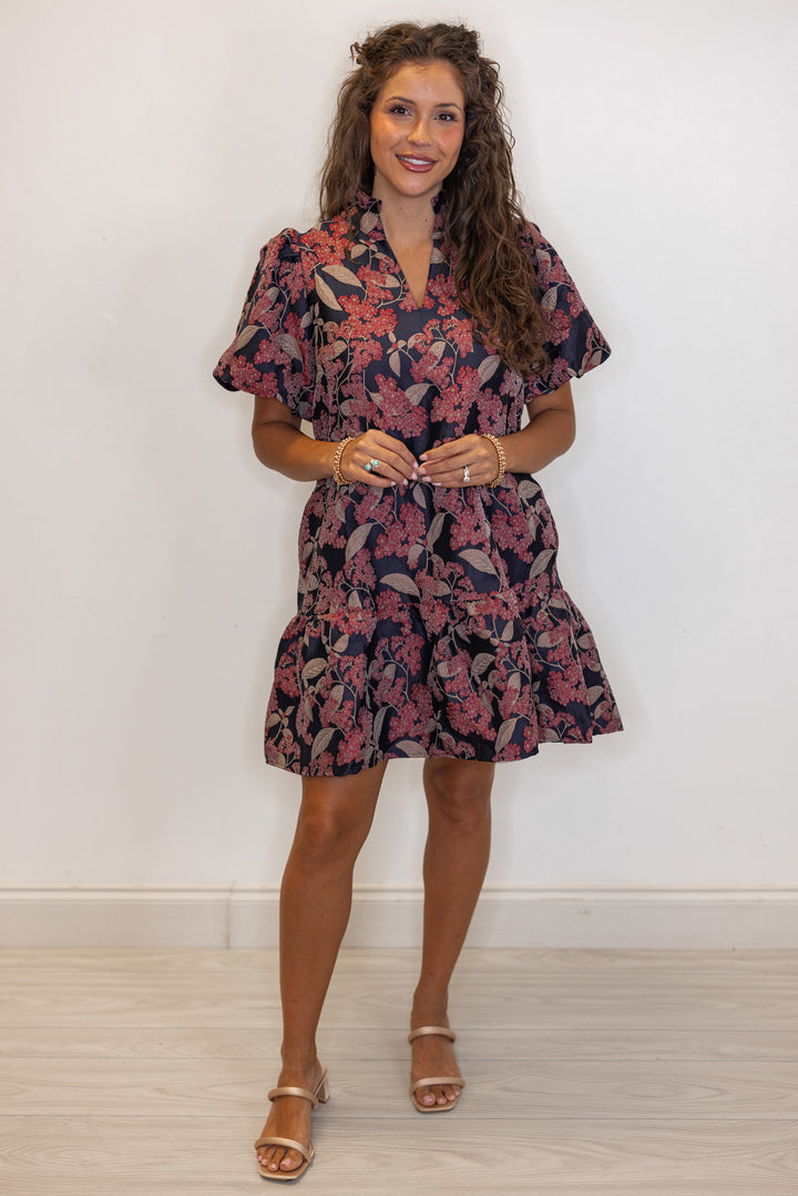 Woman's burgundy and black floral printed dress with gold bracelets