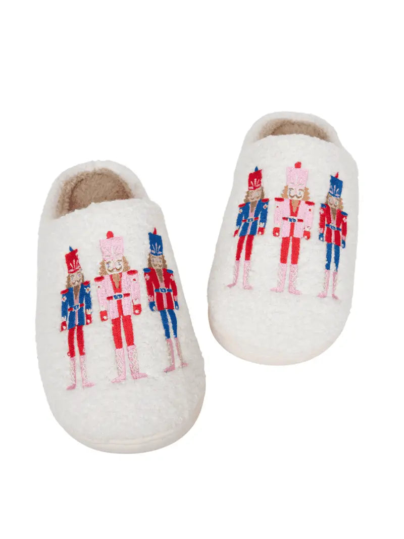 Pair of white slippers with nutcracker design on a white background