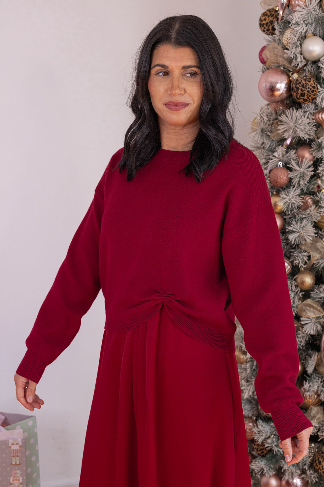 Women's burgundy knit cropped sweater top with knotted detail at the hem by Jodifl showing up close angled view