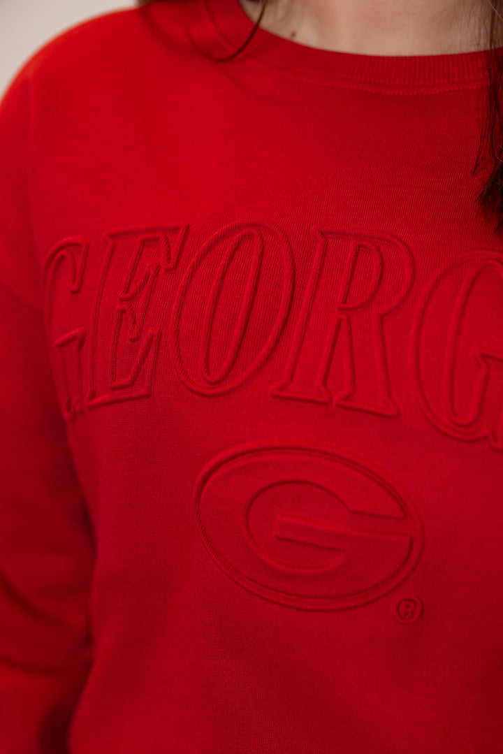 Women's red terry knit sweatshirt with embossed 'Georgia' in center by Gameday Social showing up close view of embossed lettering