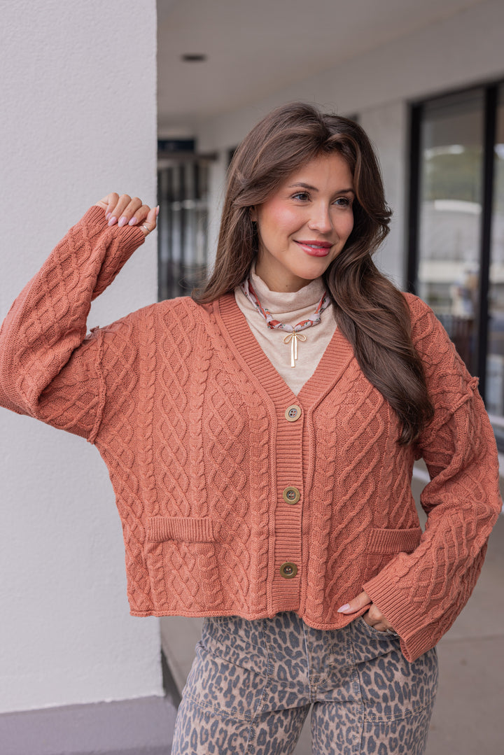 Women's terra cotta cable knit sweater cardigan by Entro showing semi-cropped length