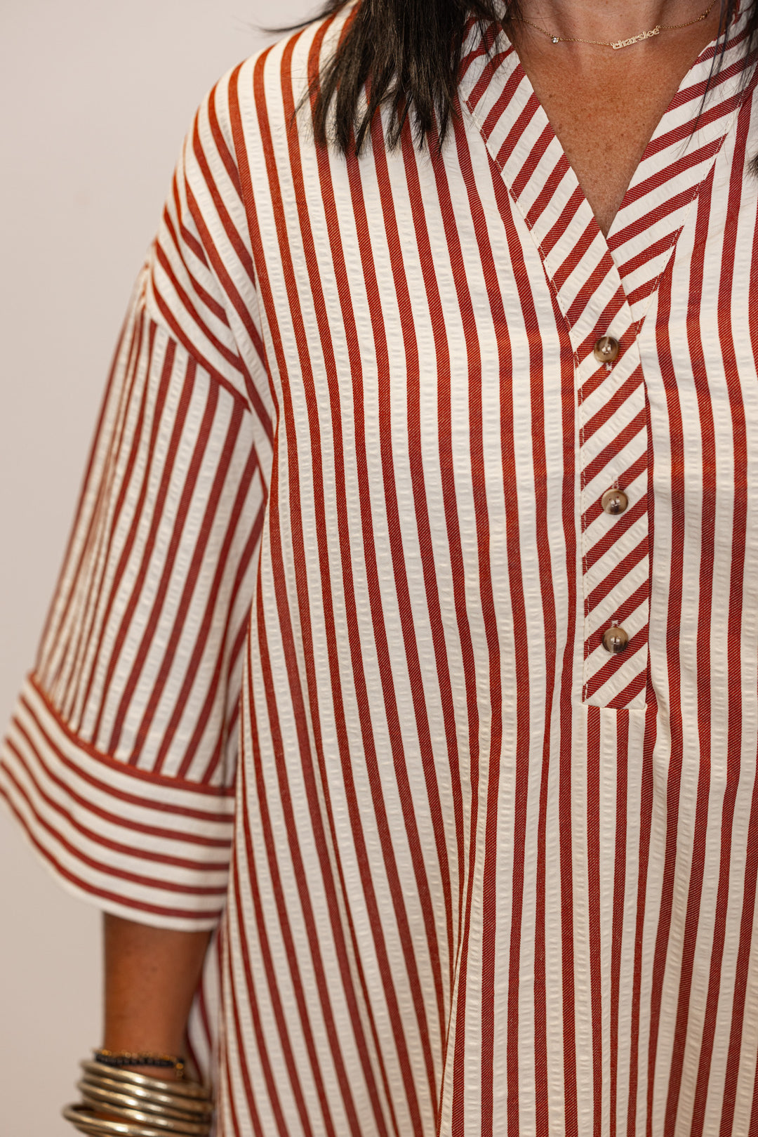 Close up of Woman's rust and ivory striped with button detail