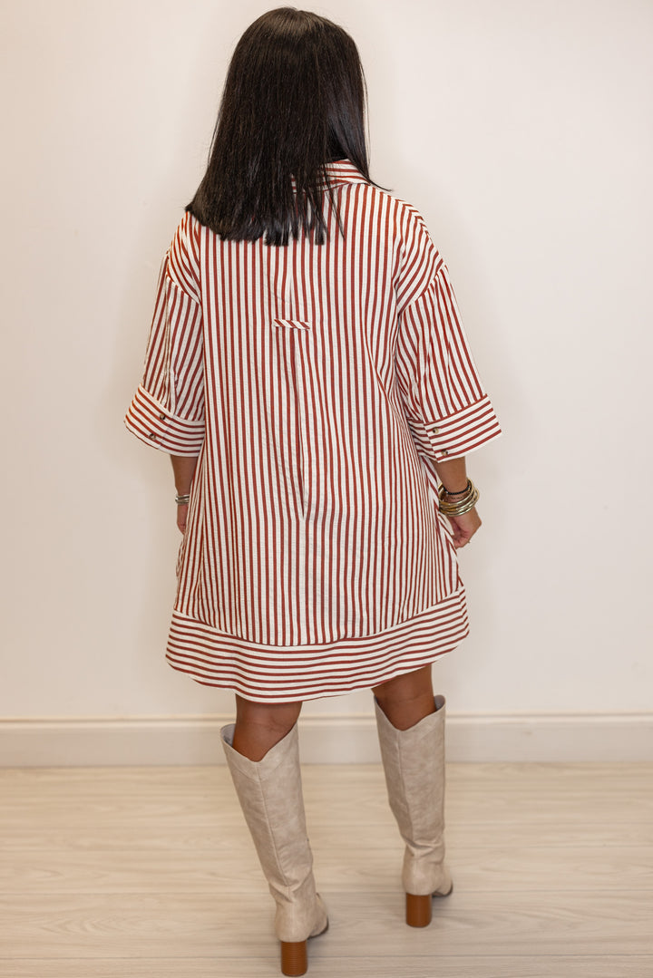 back view of Woman's rust and ivory striped dress with beige knee-high boots 