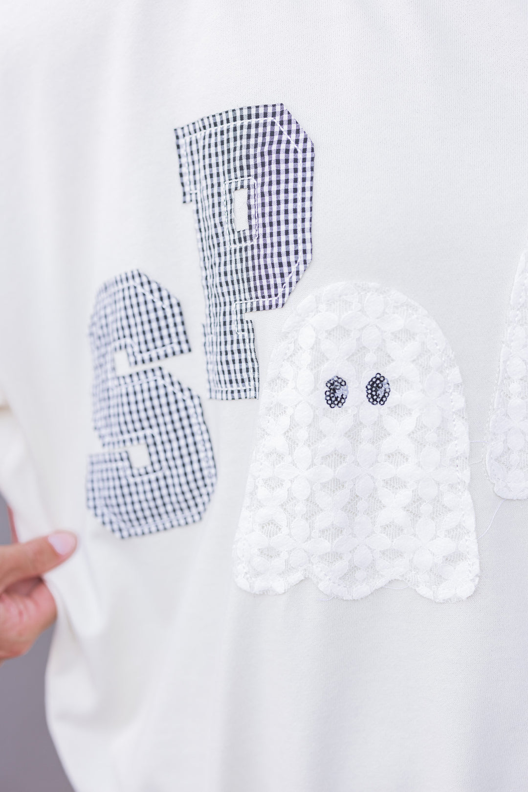 Women's cream sweatshirt with "Spooky" in lace ghosts and black checkered print by Peach Love California showing up close view of front details