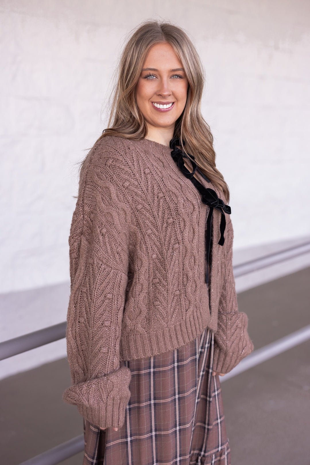Women's mocha brown cable knit sweater cardigan with black bow tie closure by Blu Pepper showing side view