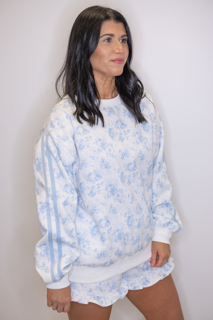 Women's light blue floral print sweatshirt showing blue striped trim down the sleeves