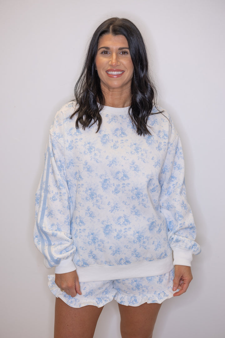 Women's cream french terry knit shorts with light blue floral print and ruffled hem shown with matching sweatshirt