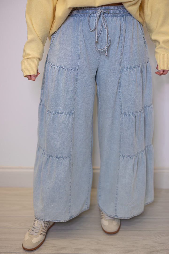 Women's light blue washed chambray denim wide leg pants with tiered detail