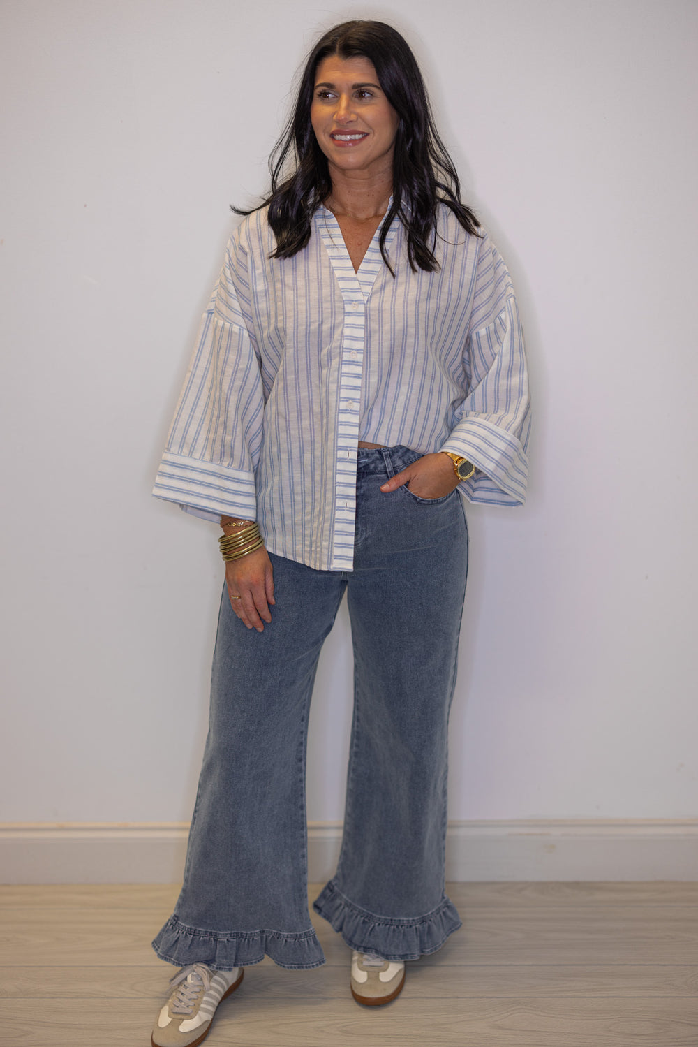 Women's light blue and cream striped button down top shown styled with an outfit