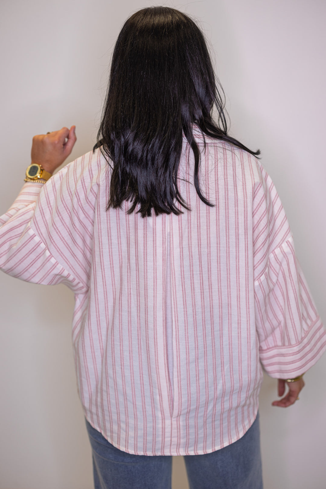Women's pink and cream striped button down top showing pleated details in the back