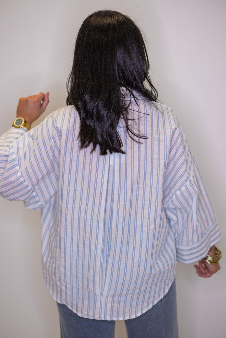Women's light blue and cream striped button down top showing pleated details on the back