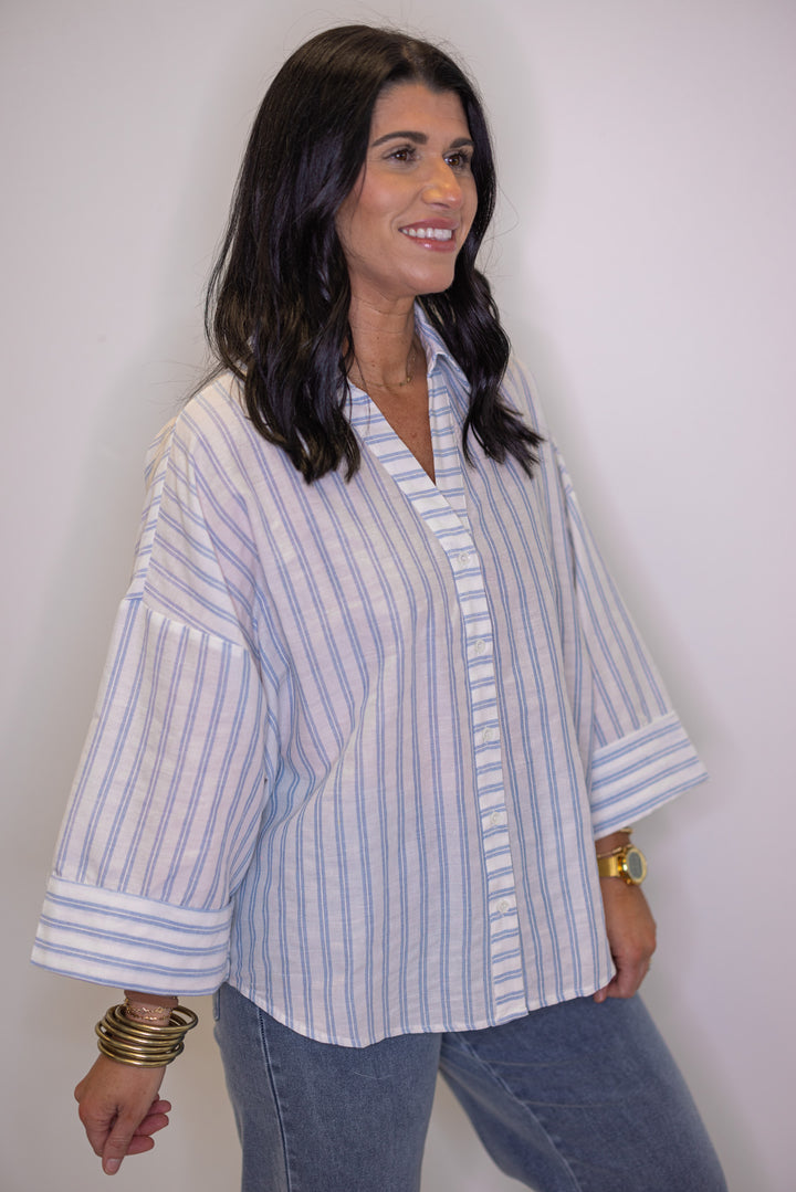 Women's light blue and cream striped button down top showing 3/4 length sleeves