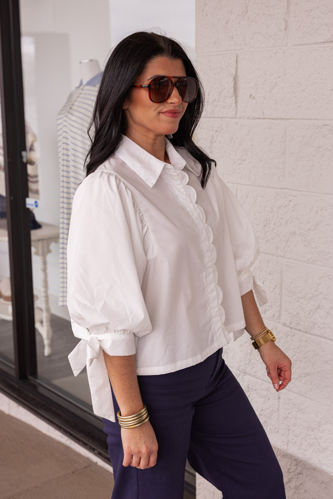 White blouse with self tie sleeve detail paired with a pair of navy pants