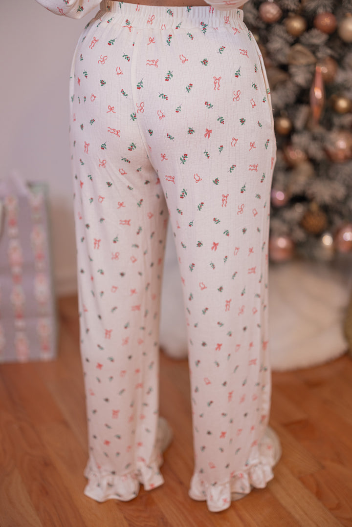 Women's cream pointelle knit pajamas with red, pink and green holly and bow tie print by Peach Love California showing pant's back view