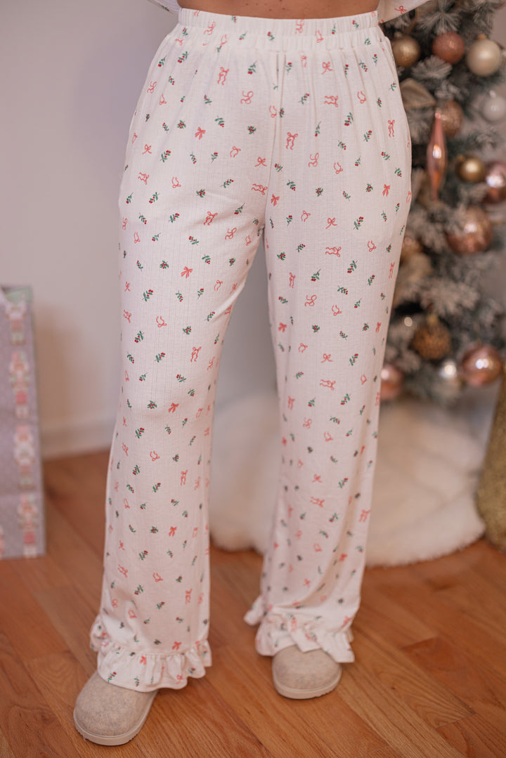 Women's cream pointelle knit pajamas with red, pink and green holly and bow tie print by Peach Love California showing pant's front view