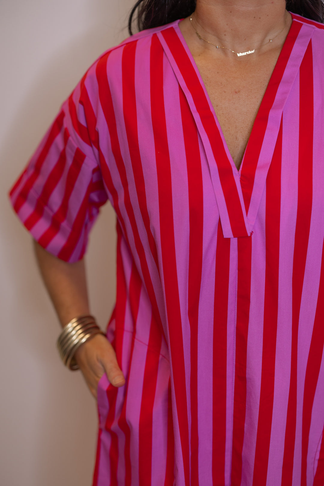 Women's red and pink striped midi dress by Entro showing v neckline with rolled trim detail