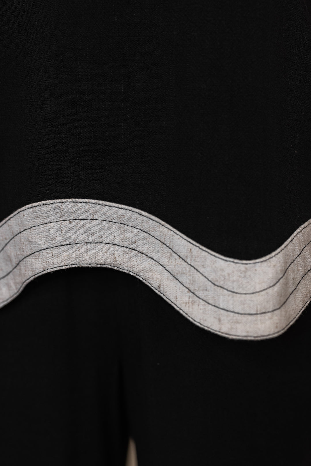 Women's Umgee black linen top showing oatmeal scalloped bottom hem 