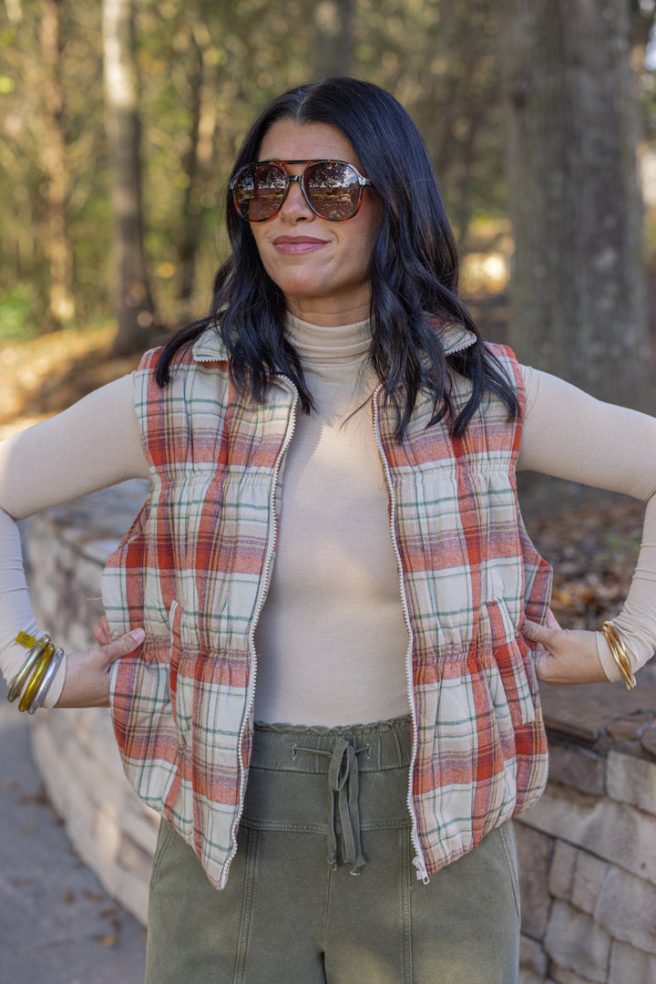 Women's quilted puffer vest in taupe, brown, persimmon orange and green plaid by Easel showing true to size fit